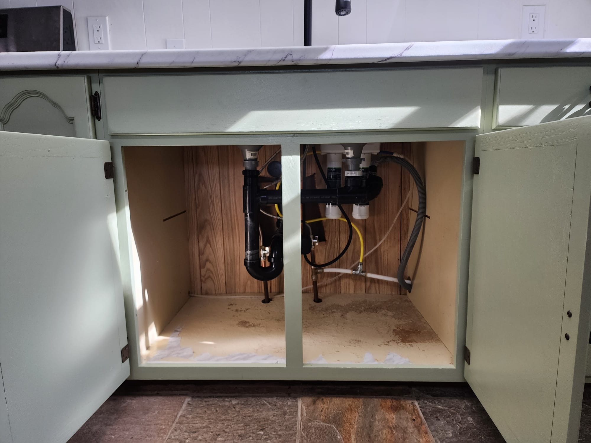 Finished under-sink cabinet with new plumbing, valves, and sage green doors