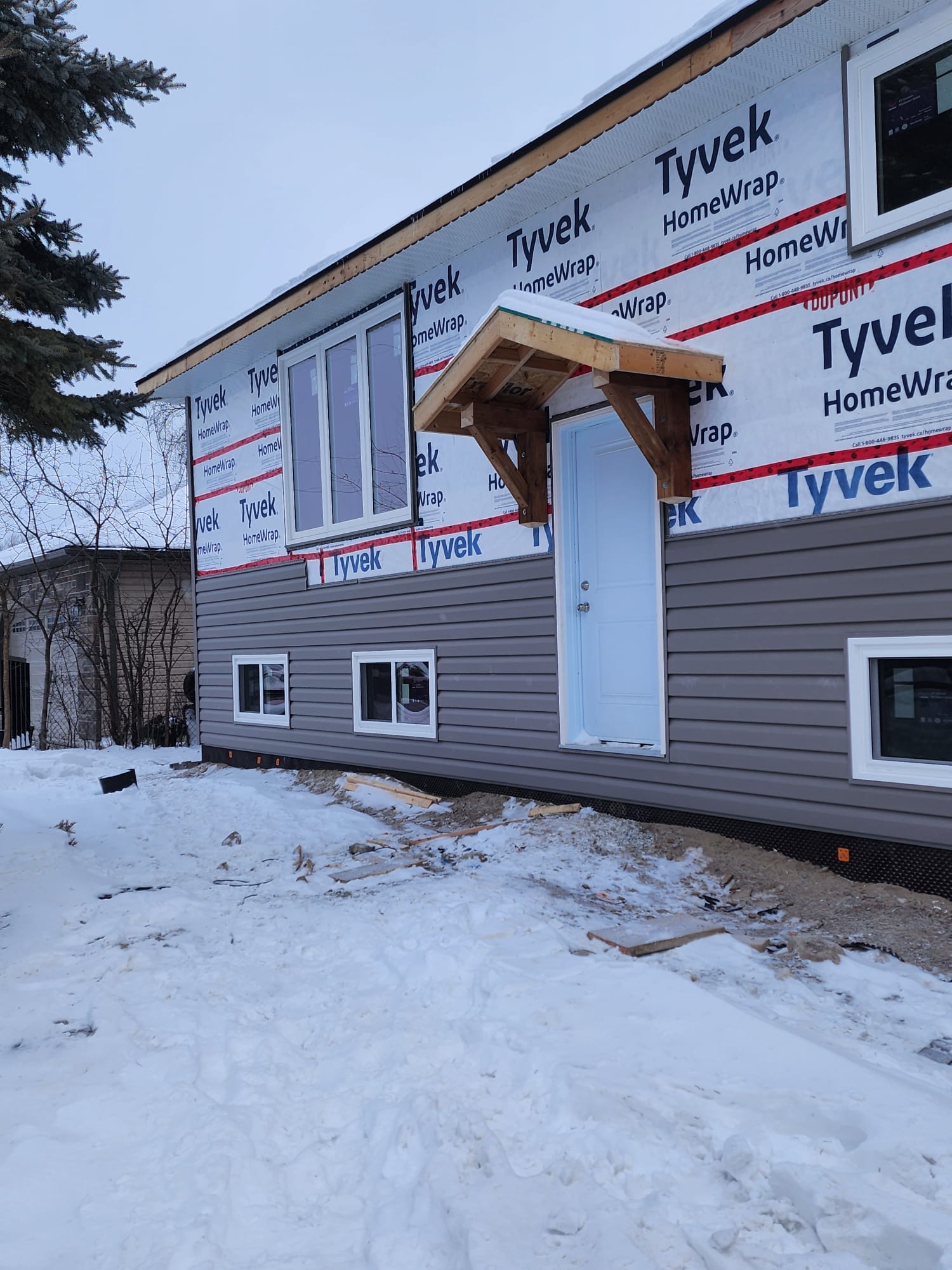 Exterior siding installation with Tyvek house wrap in winter conditions