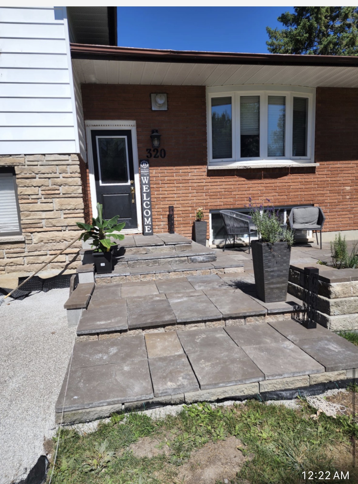 Finished front entrance stone walkway and steps leading to a brick home with welcome sign