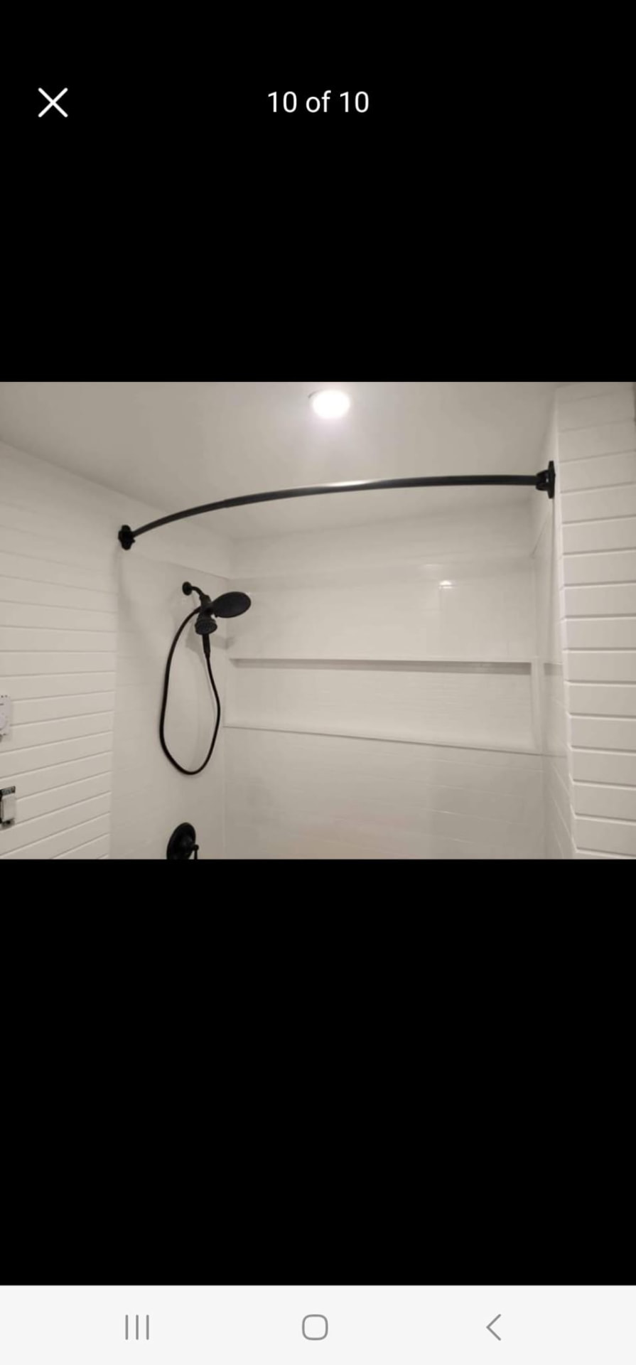 Walk-in shower with matte black curved rod, white subway tile, and black fixtures