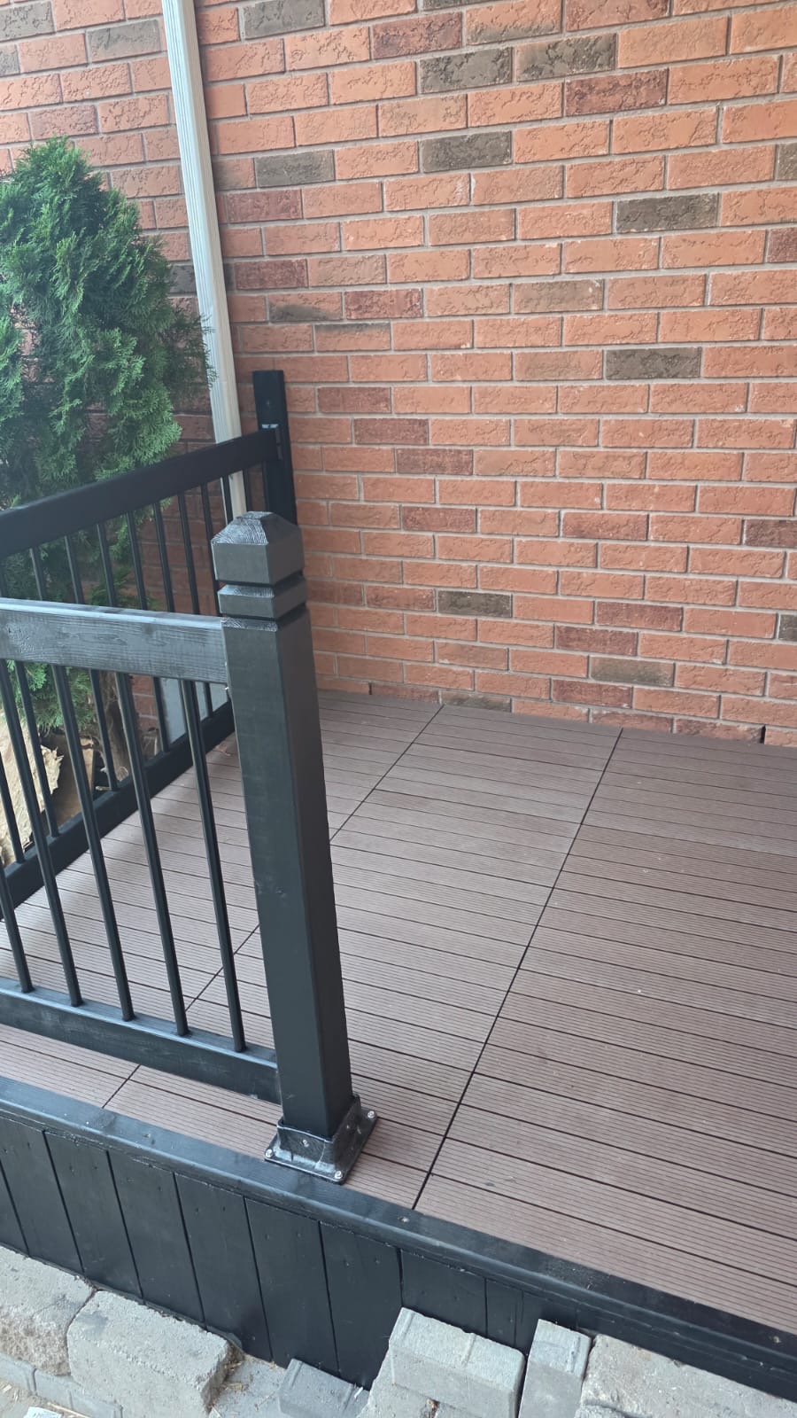 Composite deck with black aluminum railing and black skirting against brick