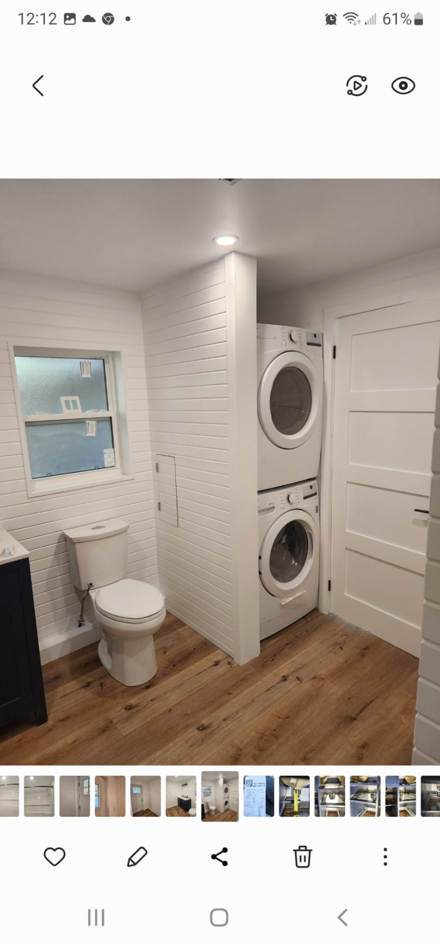 Combined bathroom and laundry room with stacked washer and dryer, shiplap walls, and hardwood floor