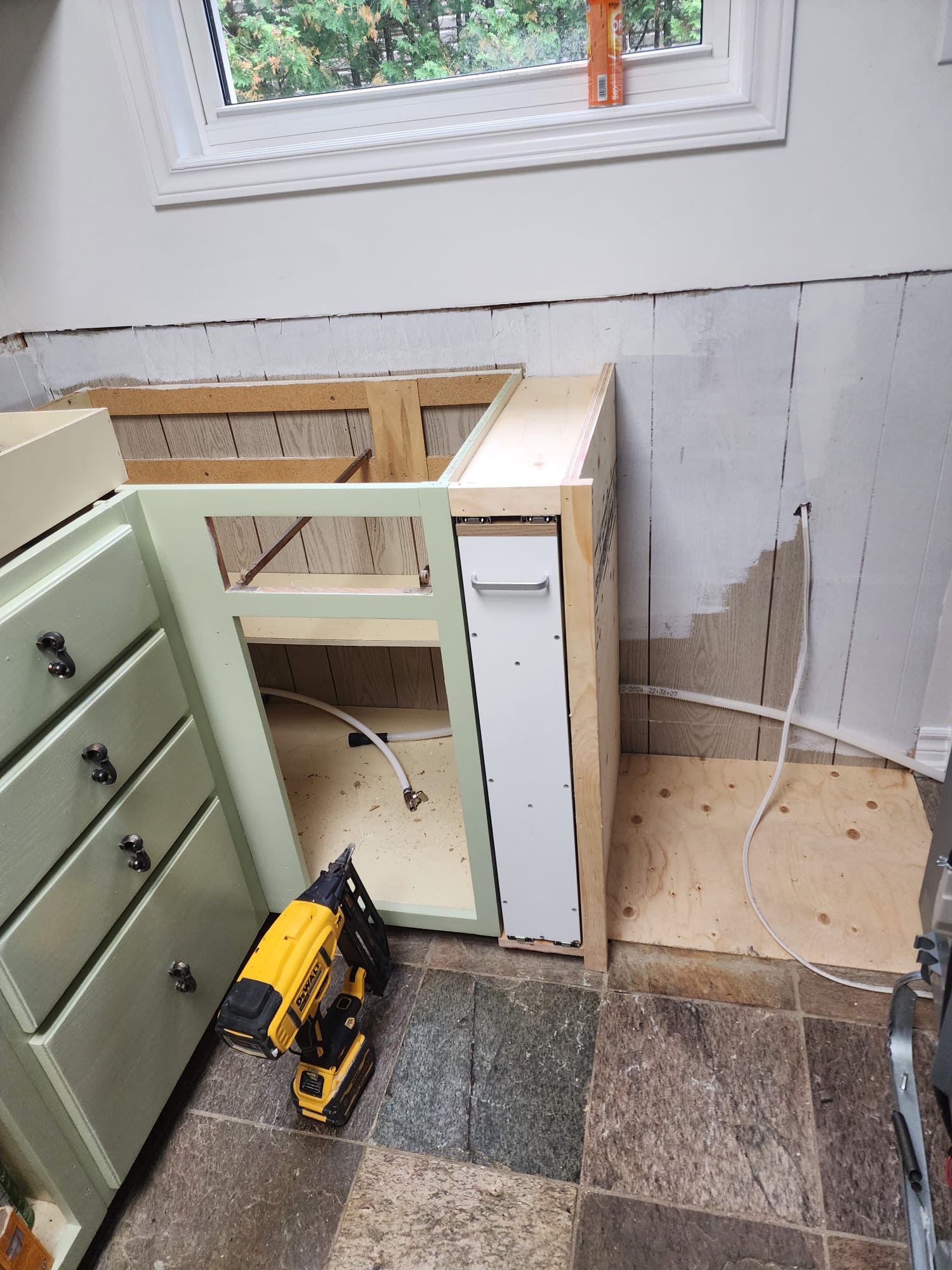 Kitchen cabinet installation in progress with pull-out drawer unit and tools