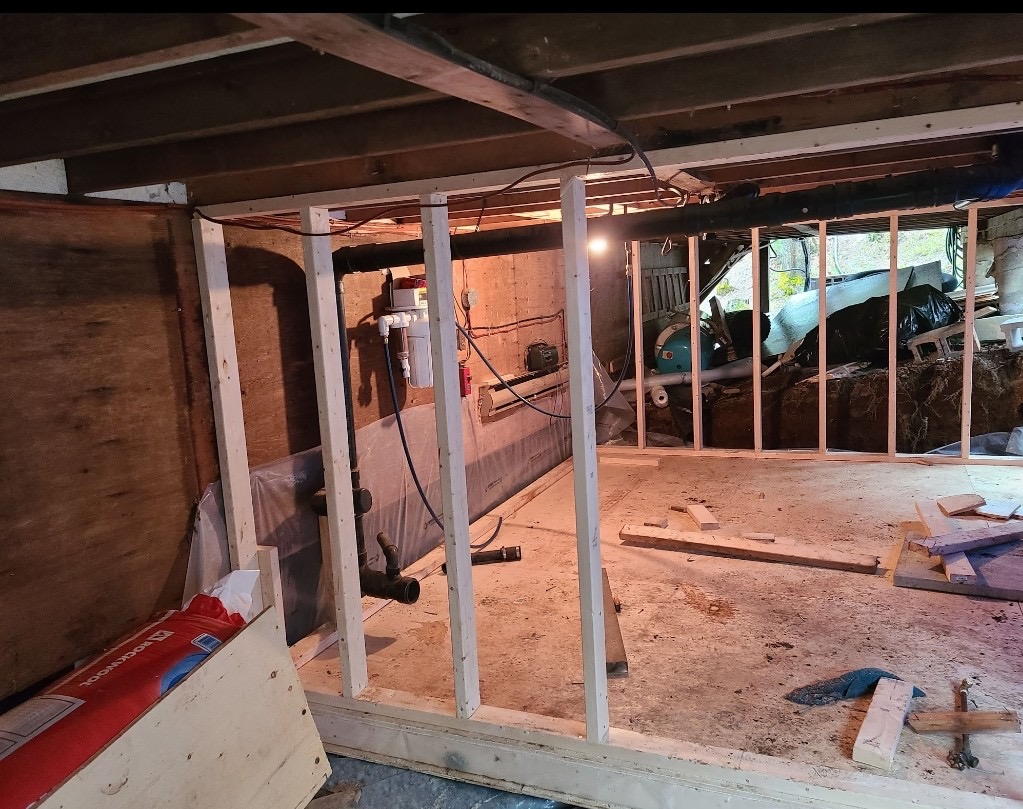 Interior basement wood stud framing with plumbing rough-in and exposed utilities