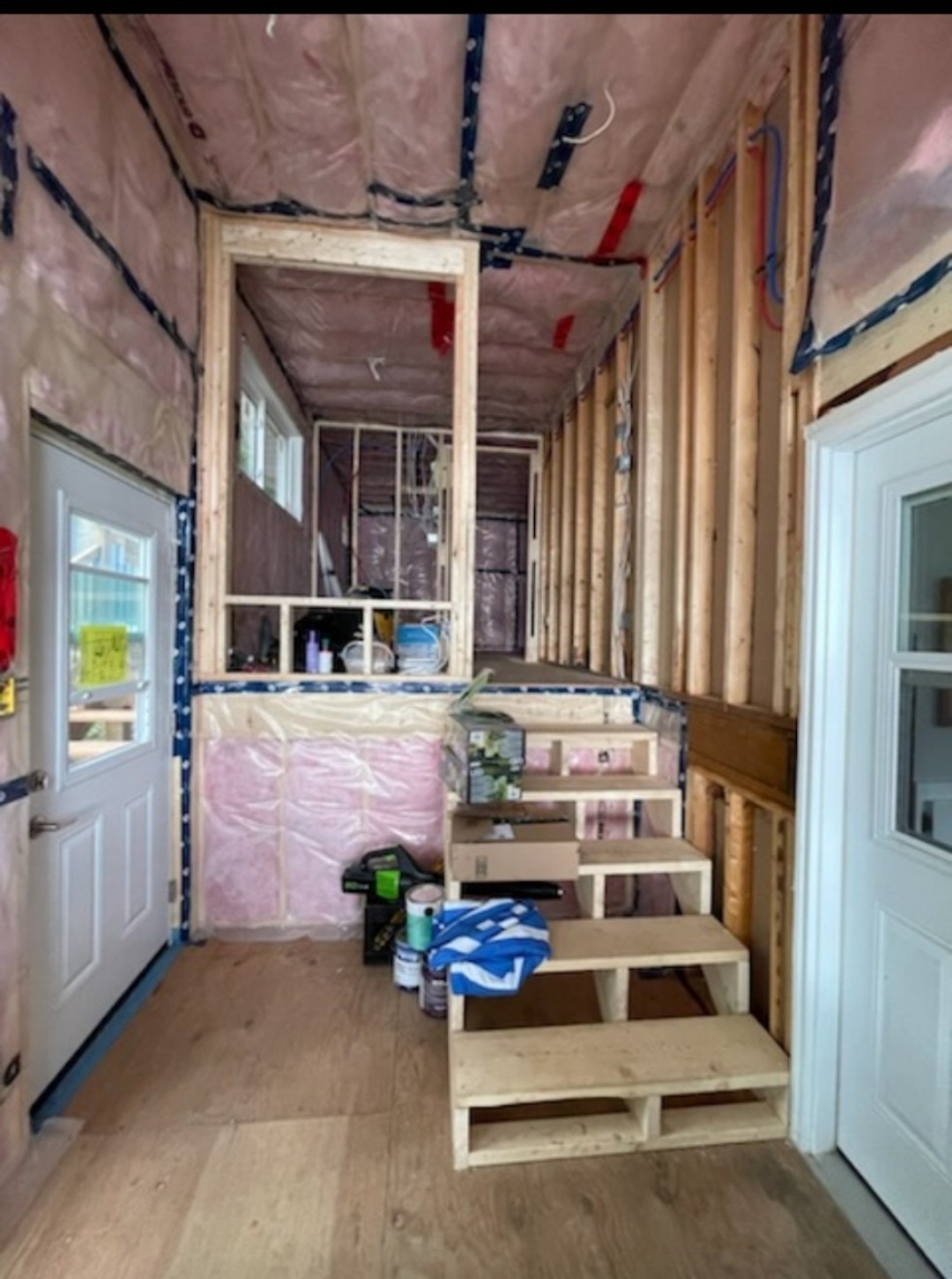 Interior entry stair framing under construction with temporary wooden steps and insulation