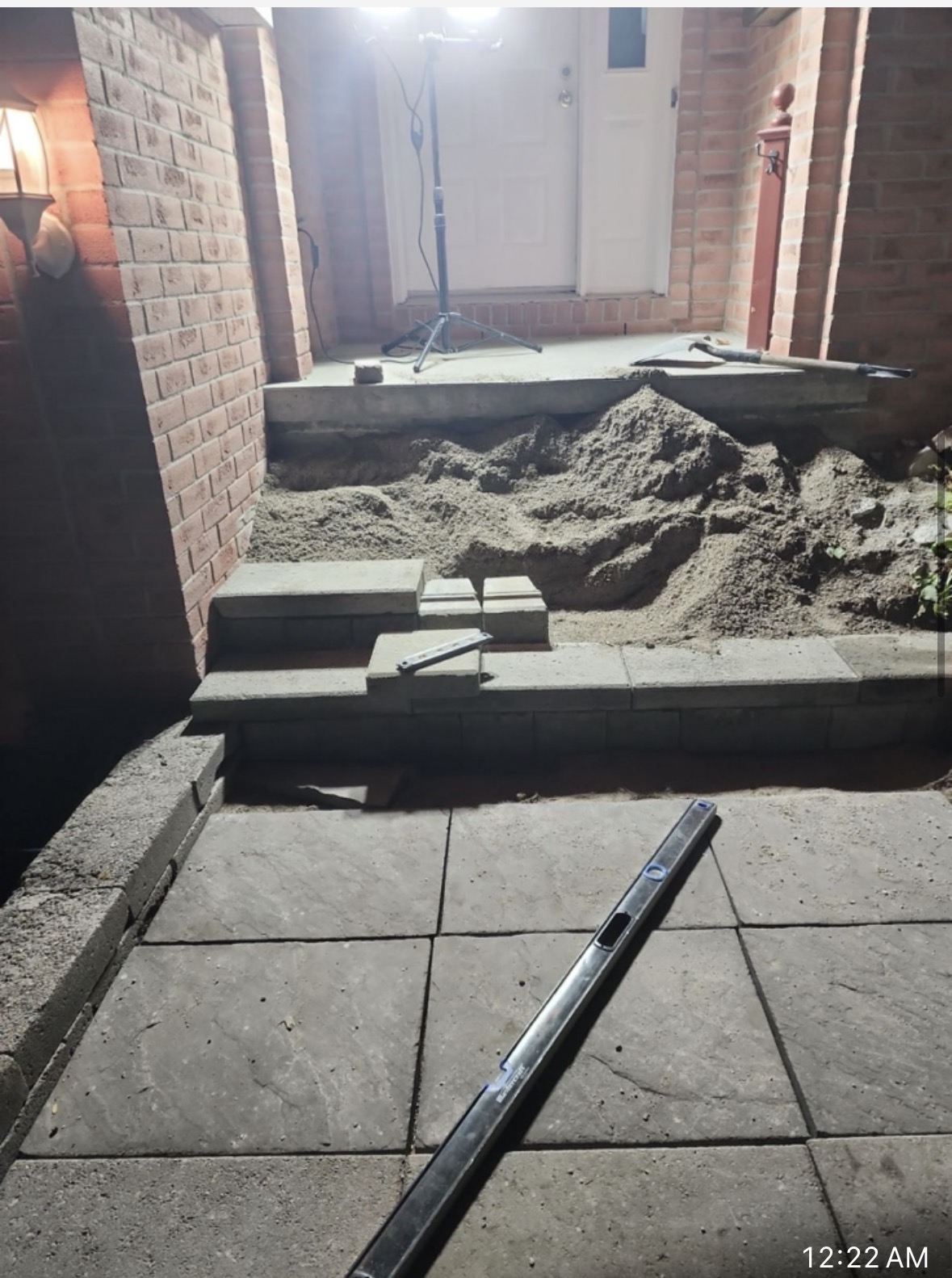 Front entrance stone steps and patio under construction at night with work light