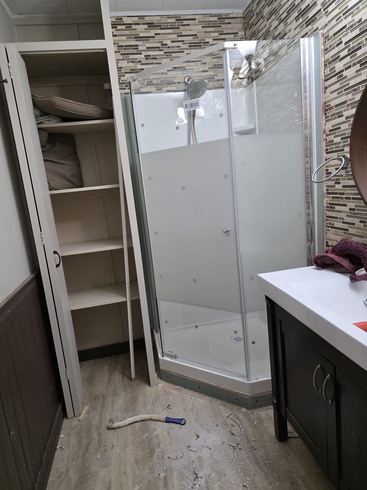 Bathroom renovation in progress with new shower stall, vanity cabinet, and mosaic accent tile
