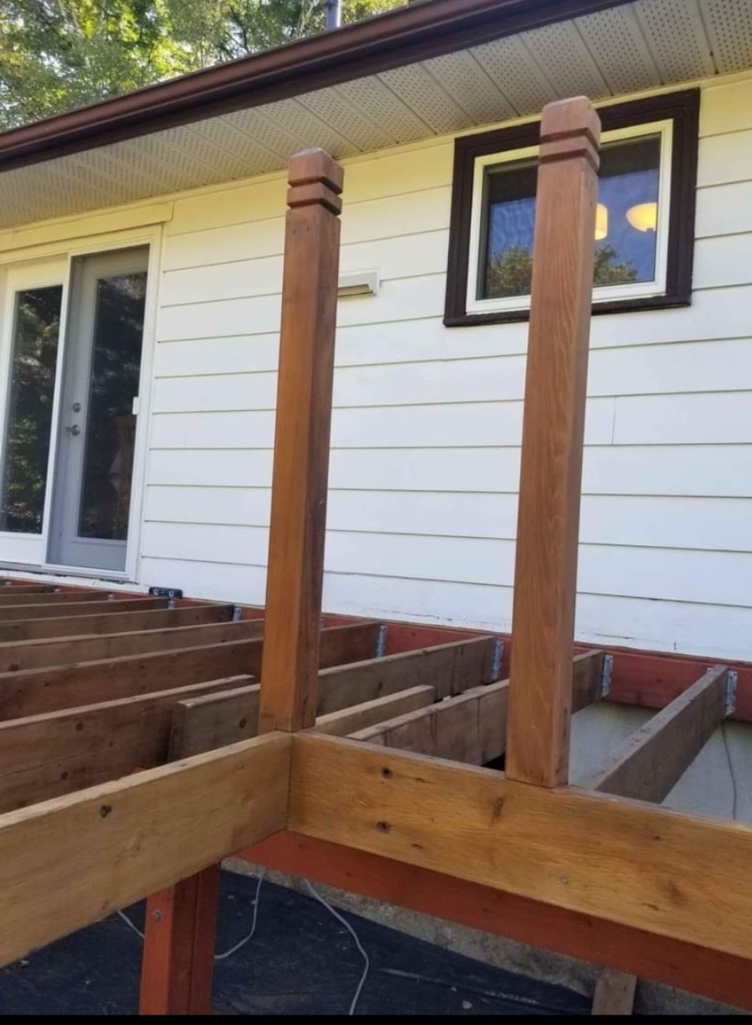 Deck framing in progress with pressure-treated joists and cedar railing posts