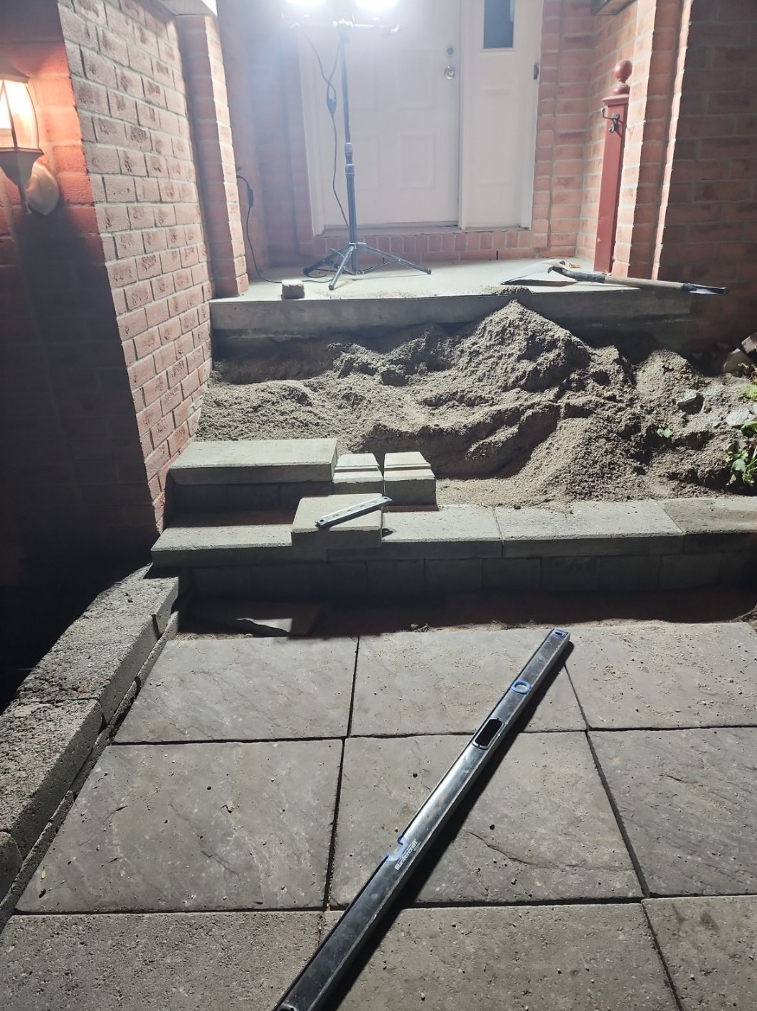 Nighttime construction progress on stone steps and patio base with level