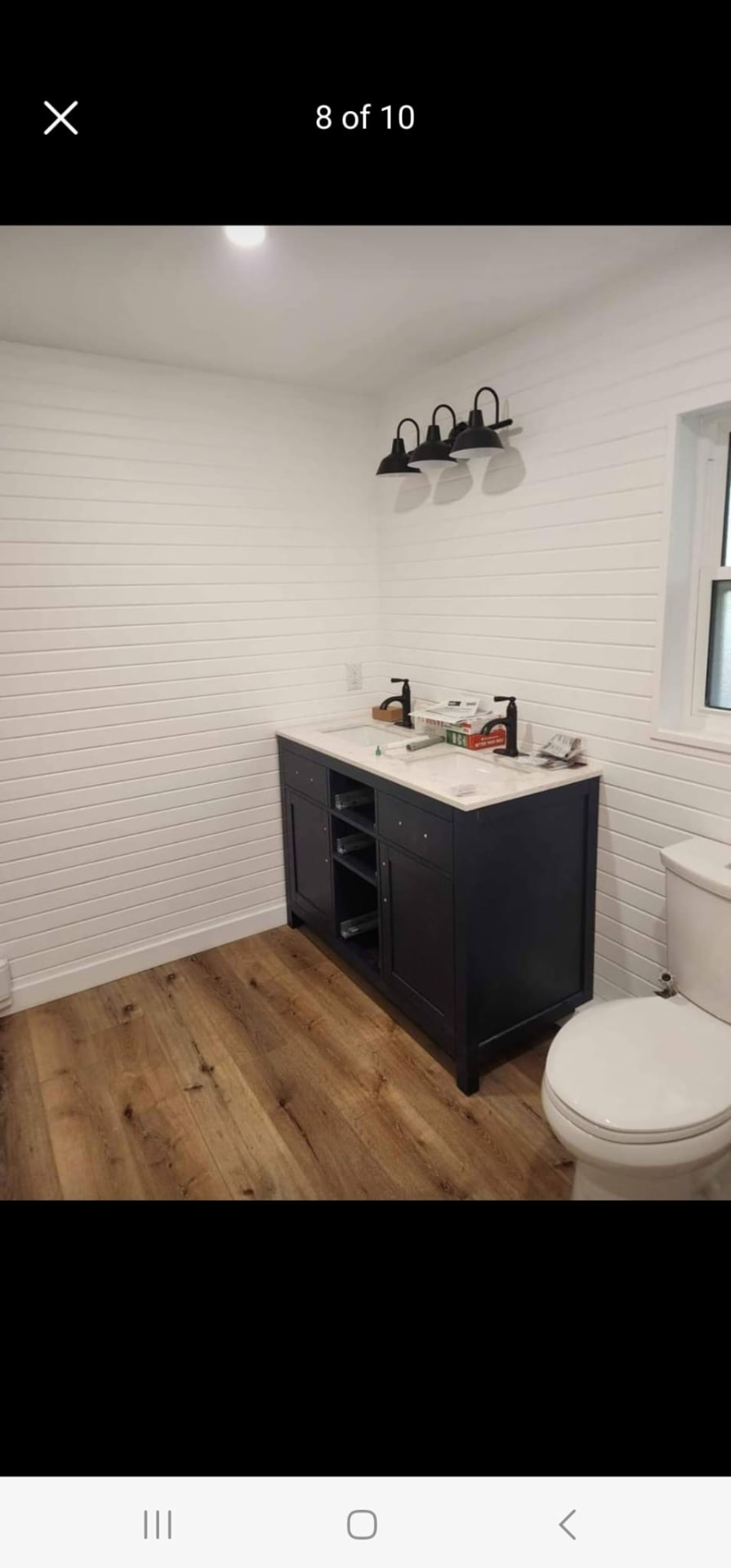 Bathroom with dark navy double vanity, white shiplap walls, and matte black fixtures