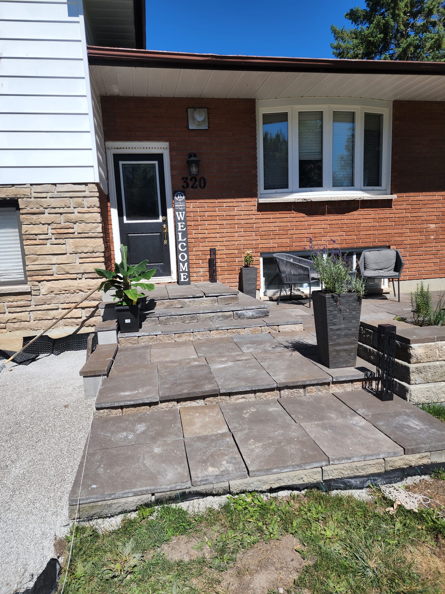 Brick home front entrance with new stone steps, walkway, and welcome sign