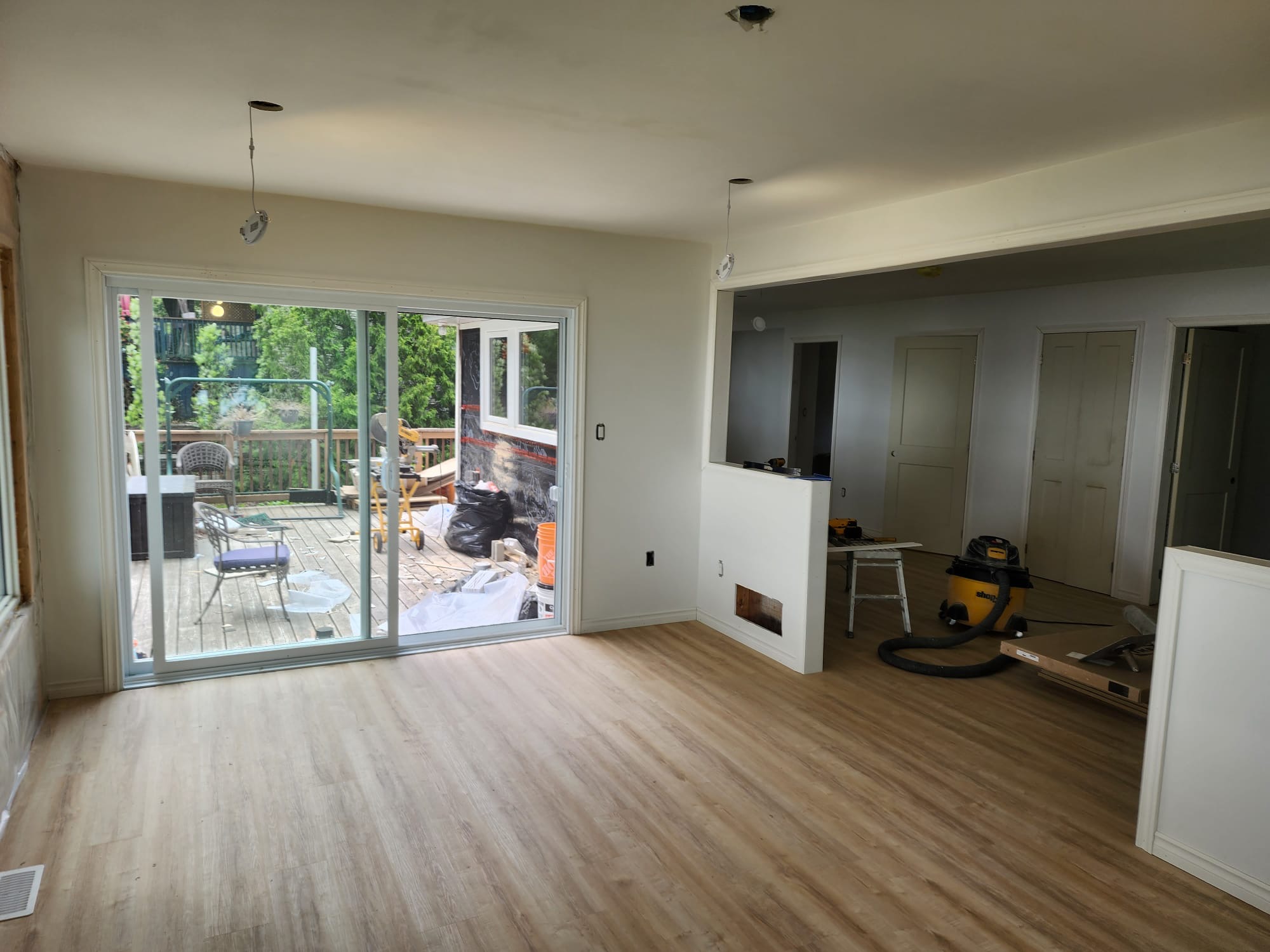Freshly painted room addition with new plank flooring, sliding patio door, and open layout