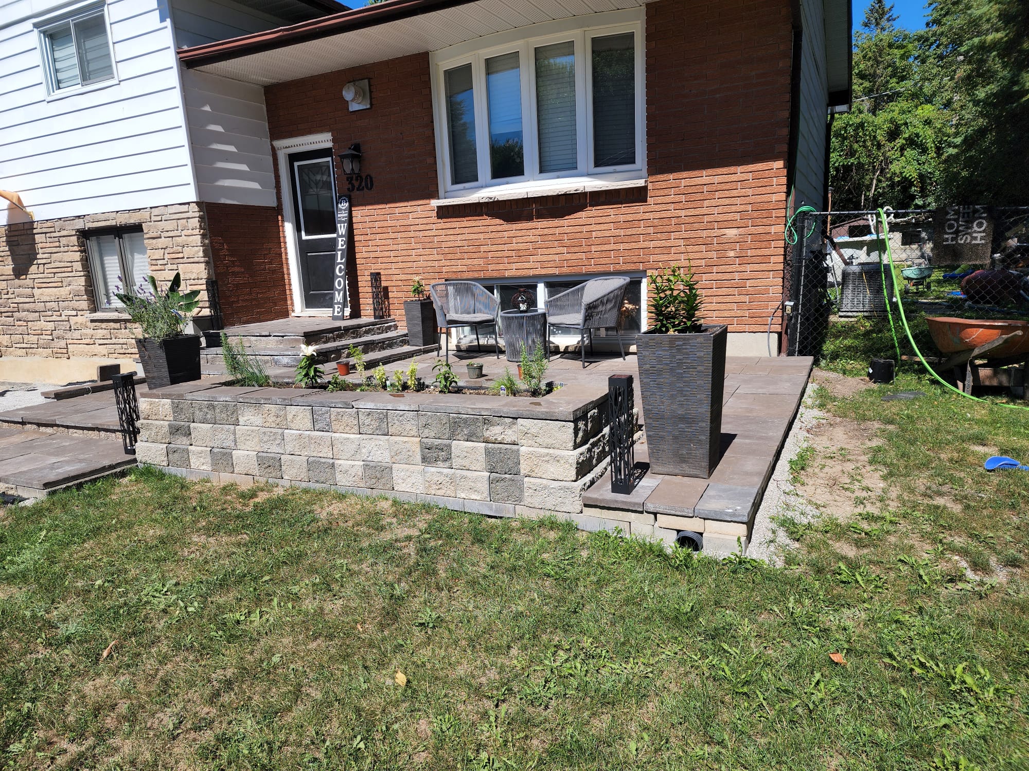 Wide view of a raised stone patio with retaining wall, steps, and garden bed