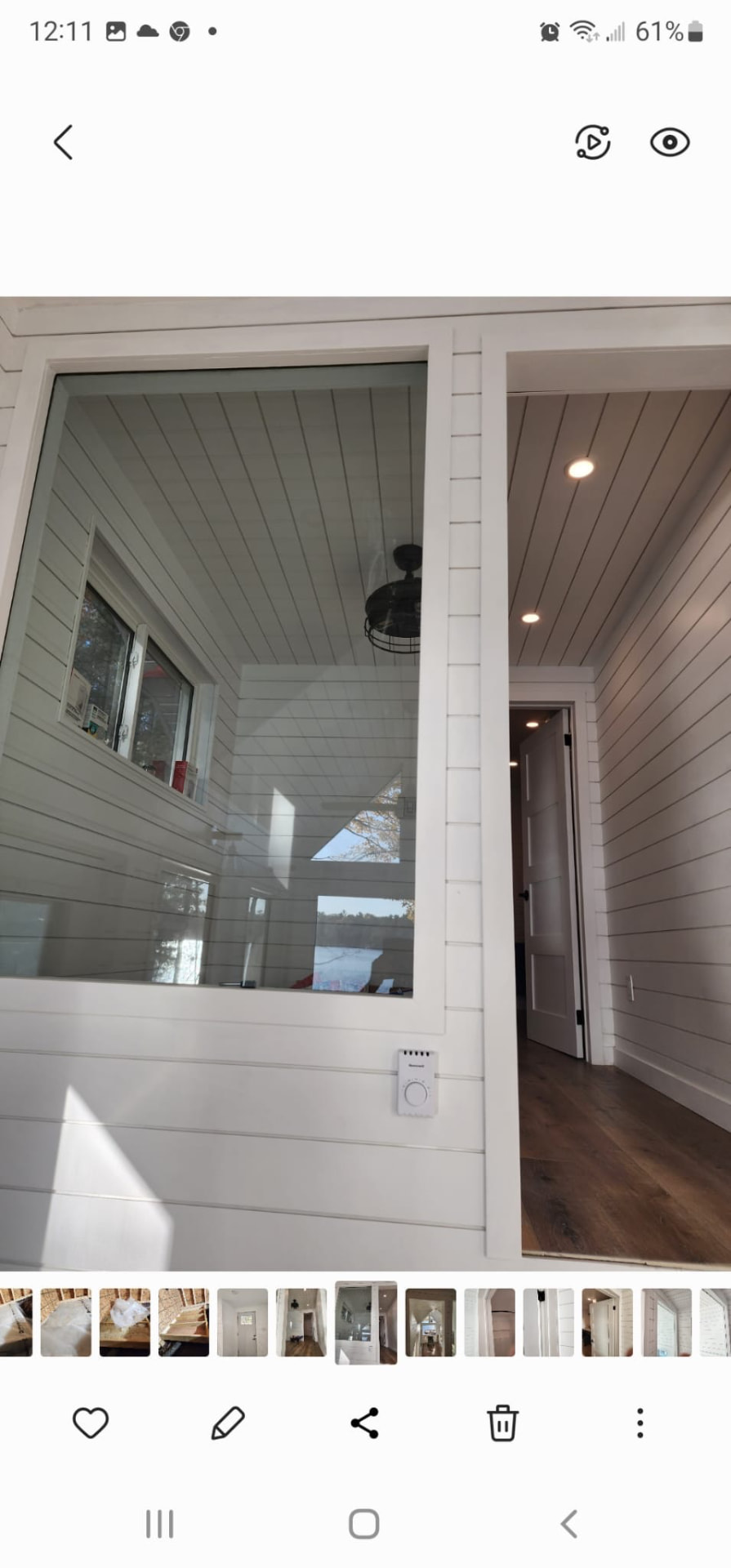 Interior window opening into a bright shiplap-lined room with hardwood flooring