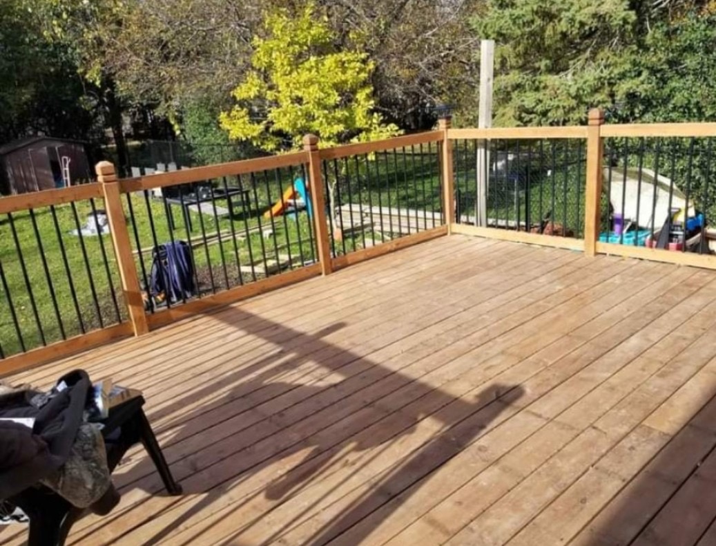 Large cedar deck with black aluminum picket railing overlooking a backyard