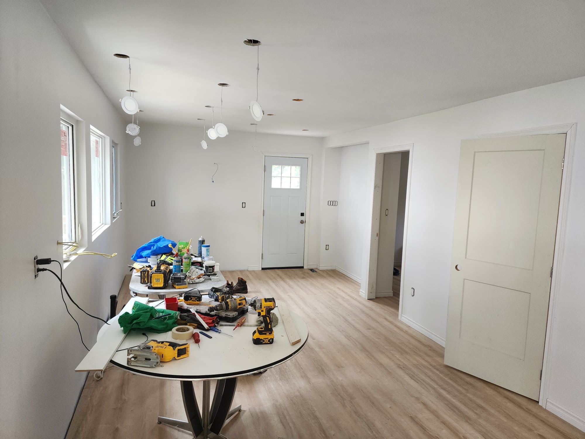 Bright finished room addition with new flooring, doors, windows, and lighting installation underway