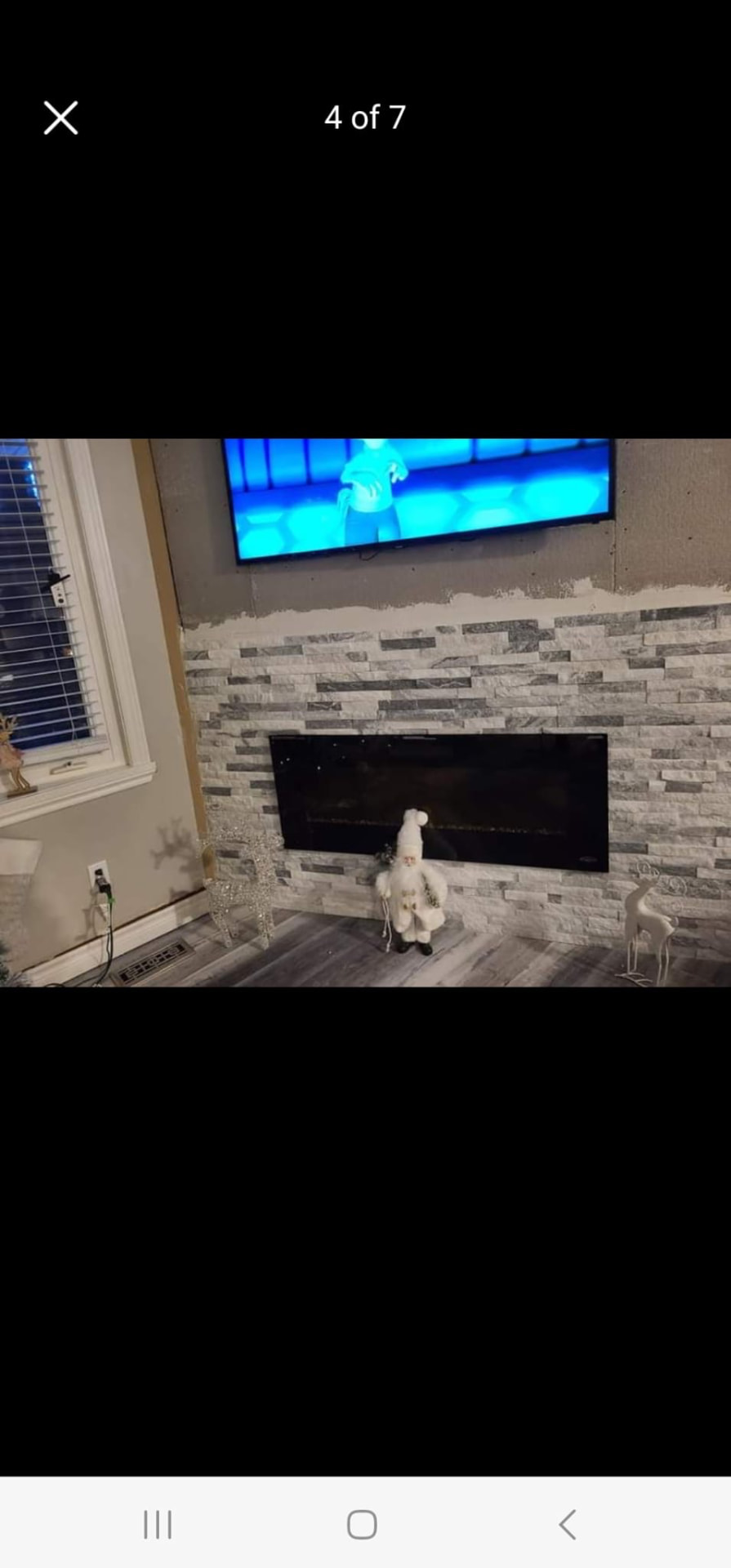 Stone fireplace feature wall partway through installation with mounted TV above