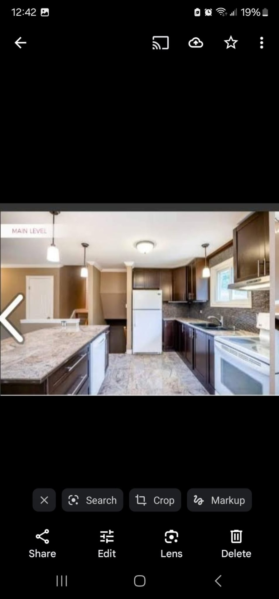 Kitchen with dark wood cabinets, granite countertops, pendant lights, and island