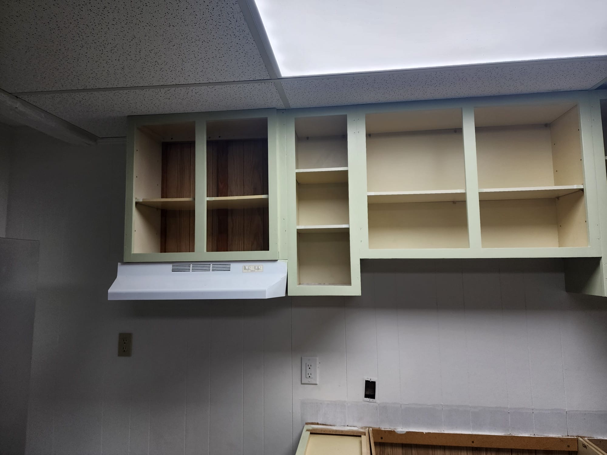 Newly installed sage green upper kitchen cabinets and range hood