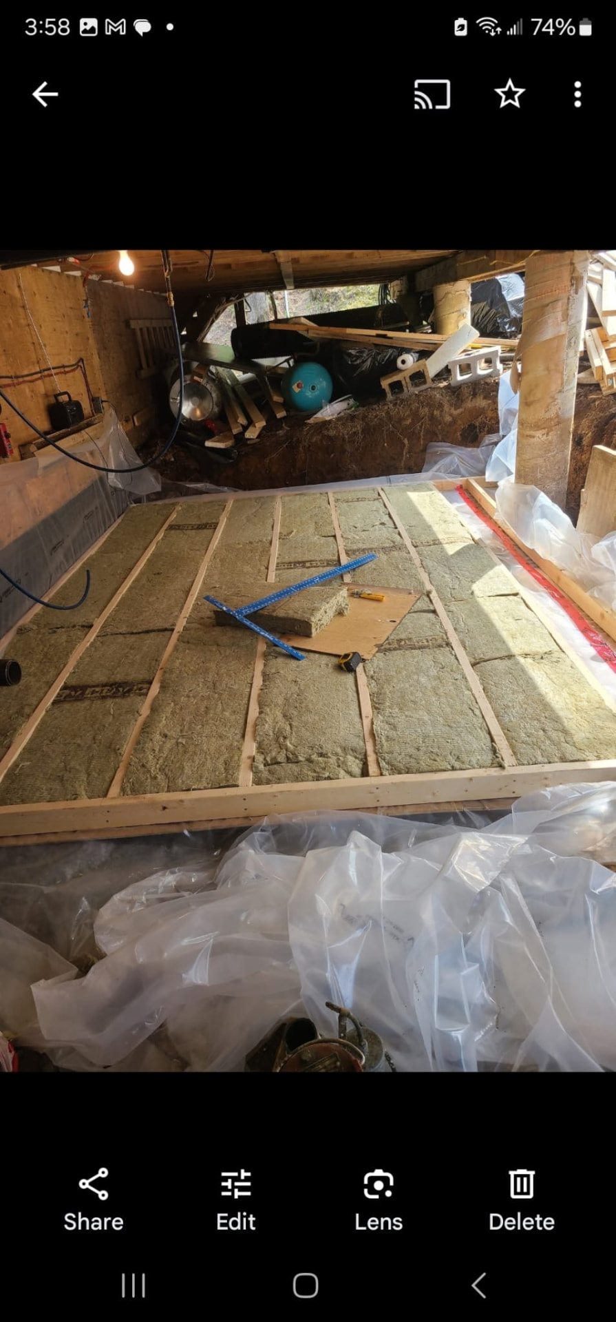 Basement floor framing with insulation batts, vapour barrier, and tools during renovation