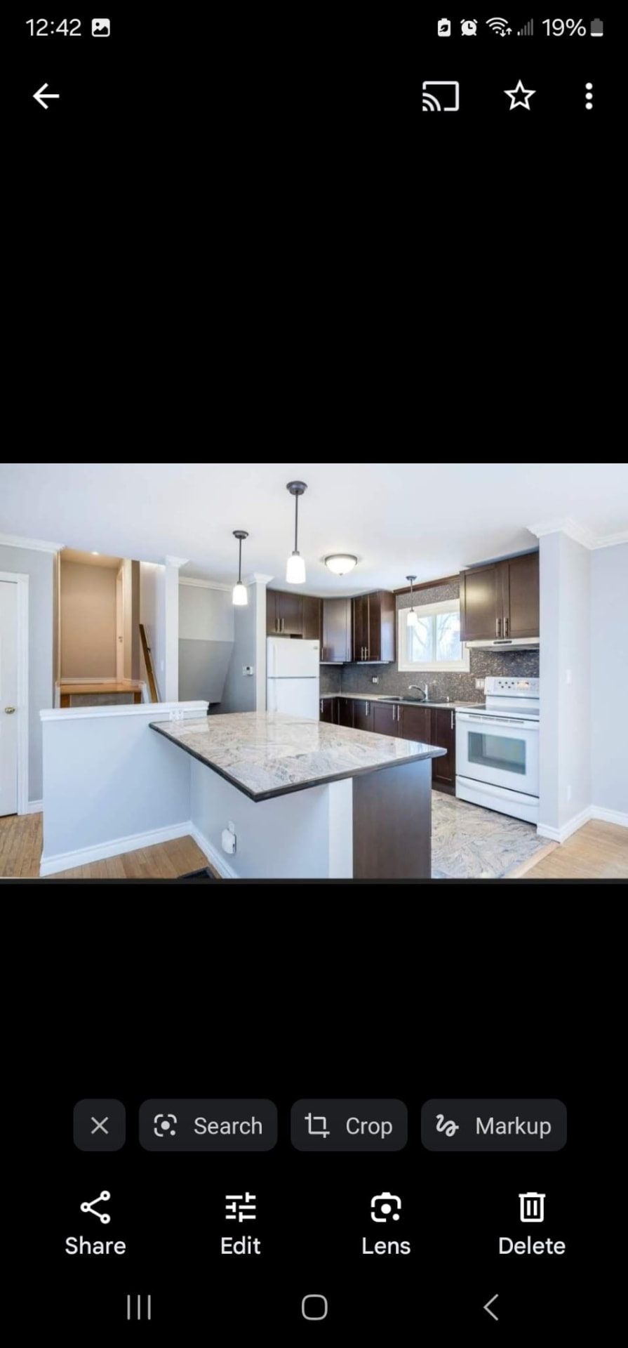 Kitchen island with granite countertop, pendant lighting, and dark wood cabinets