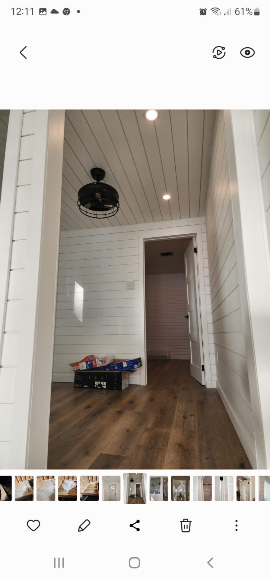 Interior hallway finished with white shiplap walls, hardwood floors, and ceiling fan