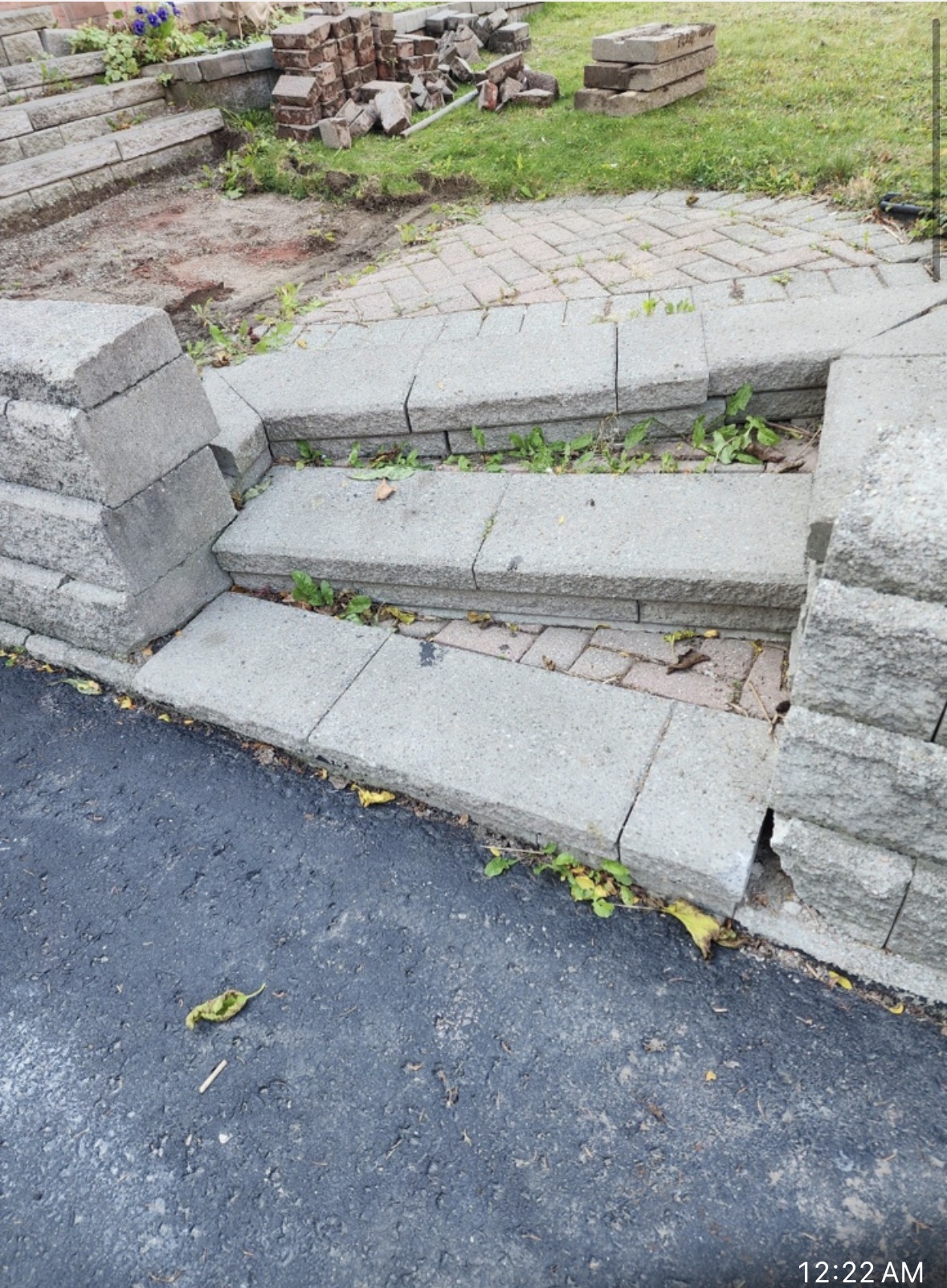 Sunken and cracked interlock stone steps with weeds growing between joints before repair